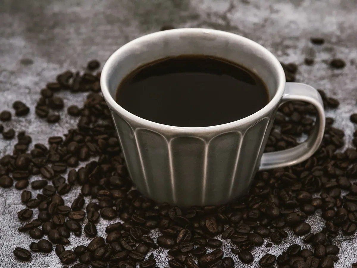 カップに入ったブラックコーヒーとコーヒー豆