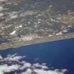 Aerial photograph of Oita Airport runway, terminal area, coastline, and sea