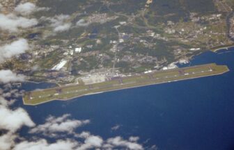 Aerial photograph of Oita Airport runway, terminal area, coastline, and sea