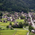 Aerial view of Shirakawa-go with gassho-zukuri farmhouses, rice paddies, and forested hills