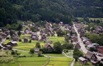 Aerial view of Shirakawa-go with gassho-zukuri farmhouses, rice paddies, and forested hills