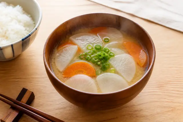 半月切りの大根とにんじんが入った味噌汁のイメージ