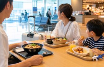 夏休み旅行で空港内のご当地フードを家族で食べながら休憩する様子