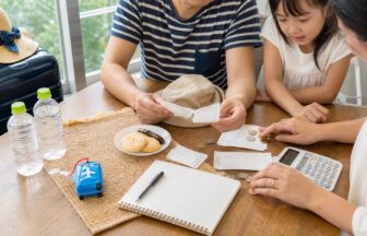 夏休み旅行の予算を交通費や食費に分けて家族で確認する様子
