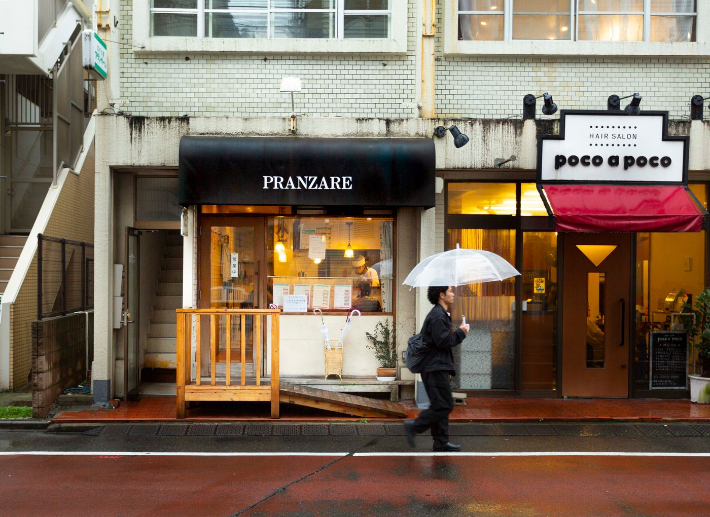 雨の日に傘を差して東京の店先を歩く人