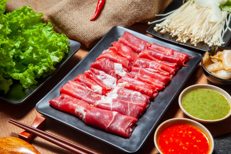 薄切り牛肉と野菜を並べた鍋料理のイメージ
