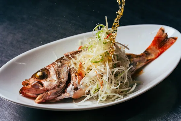 ねぎをのせて蒸し上げた魚の一皿