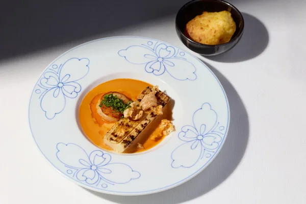 「ホタテのポワレ ココナッツとアチョーテの泡ソース 焼きパルミットとチャロン コリアンダーオイル」の説明に続けて掲載された画像
