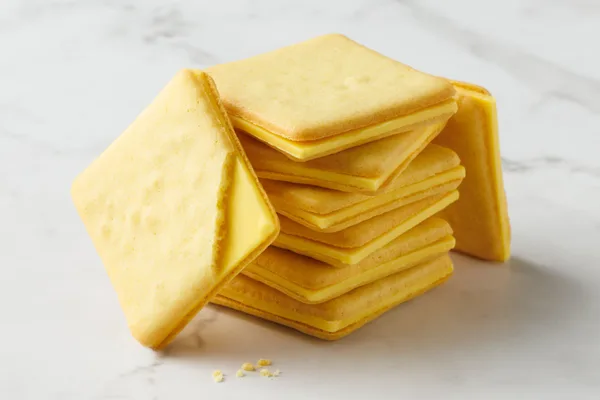 黄色いクリームを薄い四角のクッキーではさんだ菓子が積み重ねられている