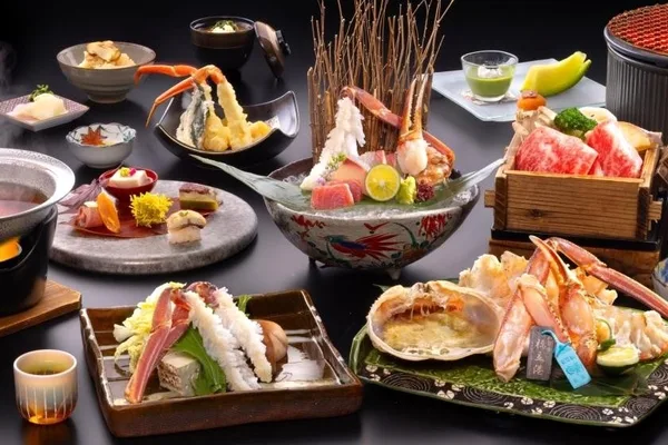蟹の刺身、焼き蟹、天ぷら、鍋などの皿が卓上に並ぶ会席料理