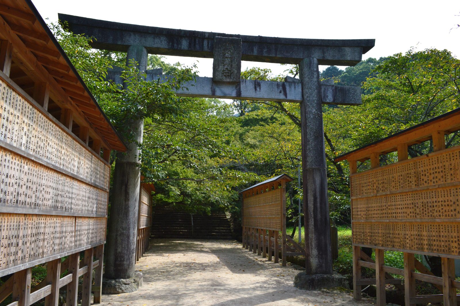 竈門神社の鳥居と参道（夏の写真）。両側に絵馬が並び、木々が茂る