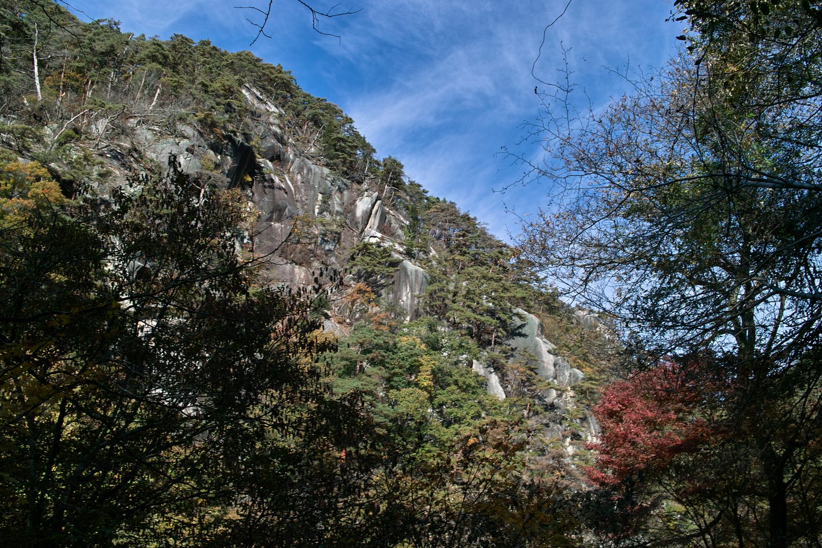 昇仙峡の花崗岩の岩壁。青空の下、岩山の斜面に紅葉が混じる