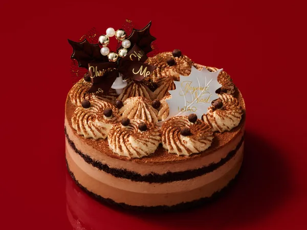 ココアをふったクリームの絞りが並ぶ、チョコレートの層が見える丸いケーキ