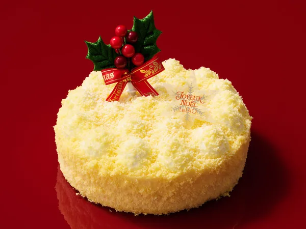 粉雪のような細かいクラムで覆われた、淡い黄色の丸いチーズケーキ