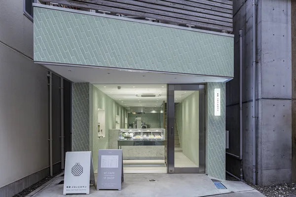 淡い緑のタイルを貼った店構え。入り口の奥にショーケースが見え、「2F CAFE 1F SHOP」の看板が立つ