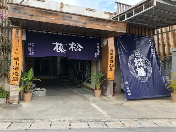 「琉球泡盛 松藤」と染め抜かれた紺ののれんが下がる酒造所の入り口