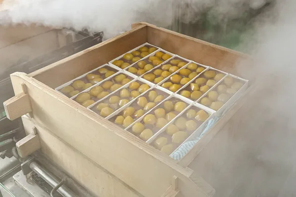 湯気の立つ木製の蒸篭の中に、栗を並べた羊羹の型が並んでいる