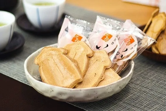 小鉢に盛られたイカの形のいかせんべいと個包装のいかせんべい、奥に緑茶の湯のみ