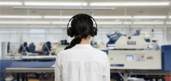縫製工場内で音声を聞きながら鑑賞する来場者