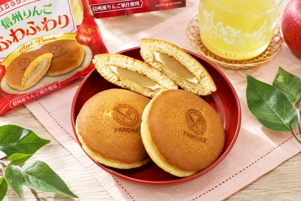 赤い皿に並ぶ焼き印入りの丸い菓子2個と、半分に切った断面。断面に淡い色の餡と白いマーガリンが見える