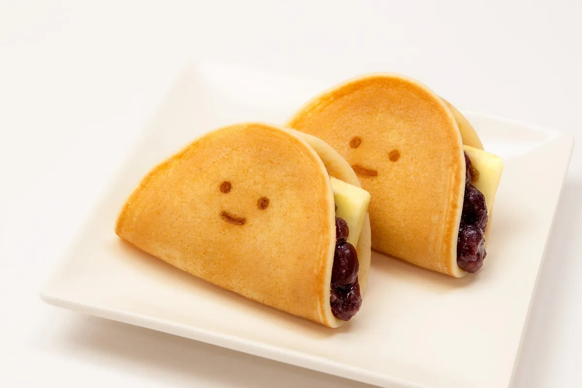 皿に載った「ふわもちつばら」2個。焼皮につばらちゃんの顔の焼印が入り、断面に小倉あんとバターが見える