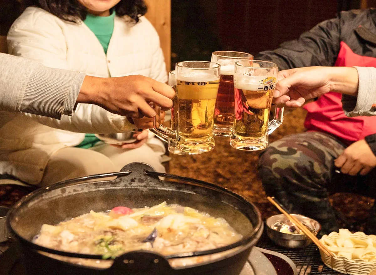 薪ストーブを囲み、温かい鍋料理を楽しむ冬の夕食