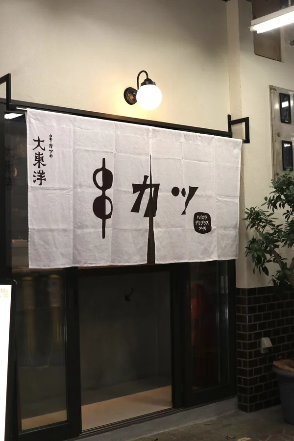 白い暖簾が目印の外観と、外飲み台